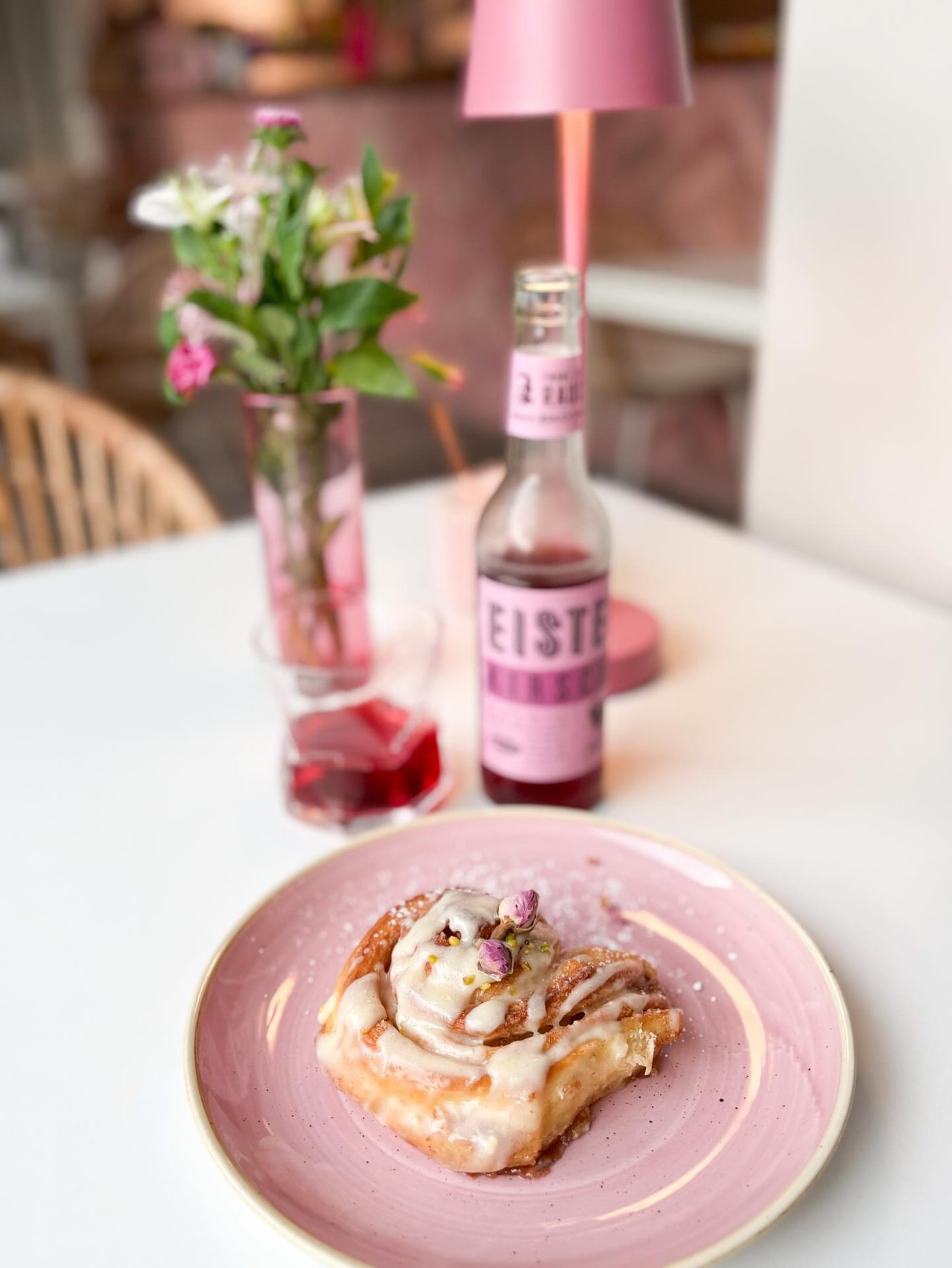 Zimtschnecke mit Zuckerguss auf einem gedeckten Café-Tisch